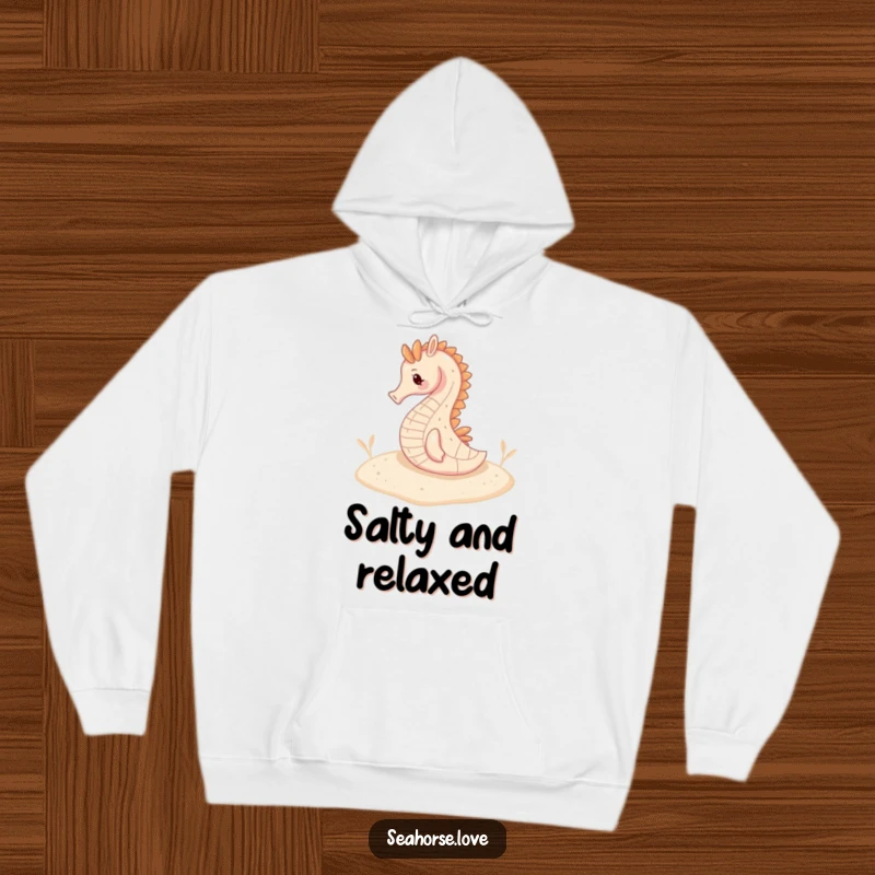 Funny hoodie depicting a seahorse resting serenely on a sandy seabed, exuding deep-sea tranquility.